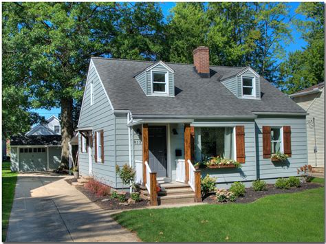 white house with grey metal.roof and.wood shutters|gray siding with blue shutters.